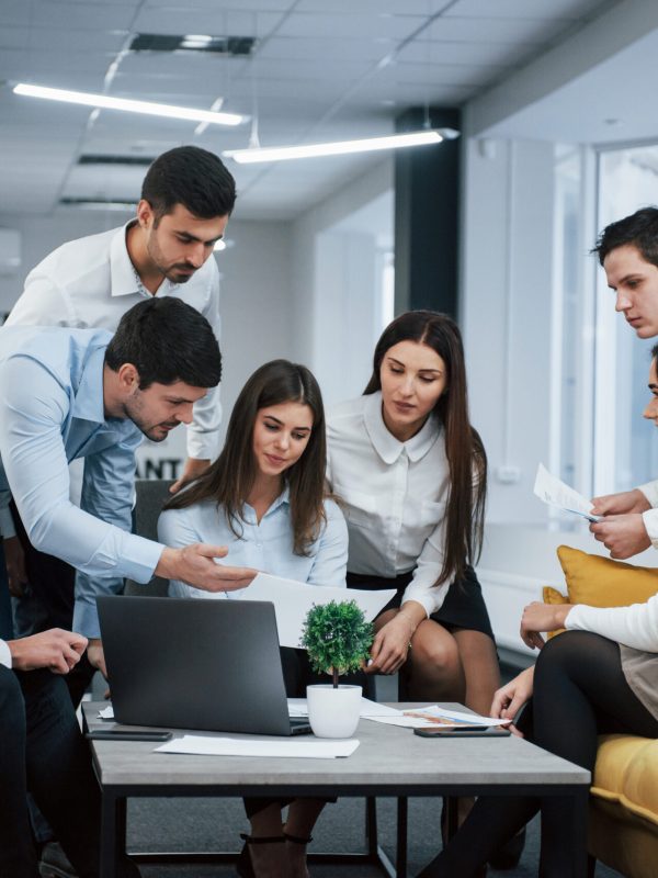 Guy shows document to a girl. Group of young freelancers in the office have conversation and working Guy shows document to a girl. Group of young freelancers in the office have conversation and working.